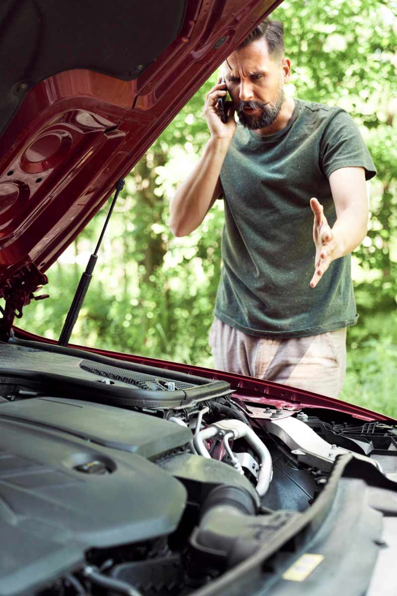 Junger Mann prüft Getriebeschaden bei Schrottauto Ankauf Würzburg